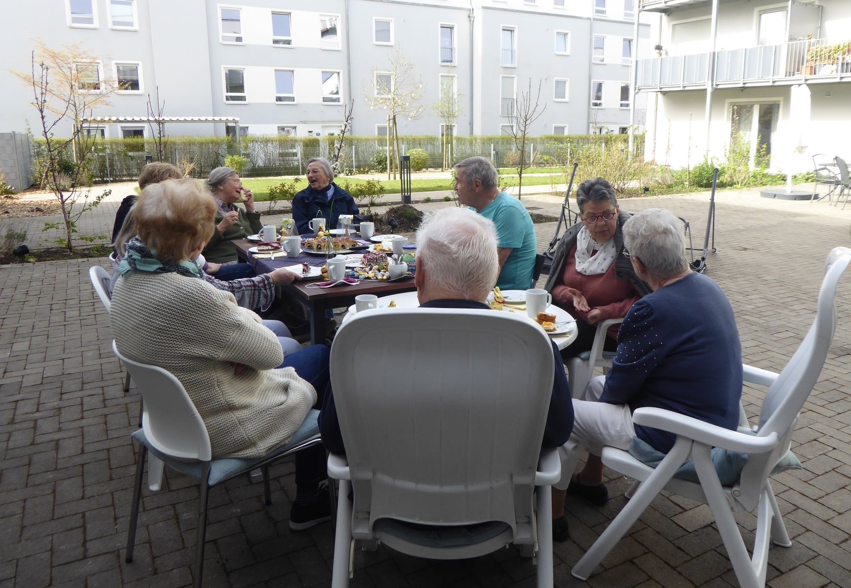 Bildmotiv zeigt Gruppe von Senioren im Aussenbereich um einen Tisch sitzend